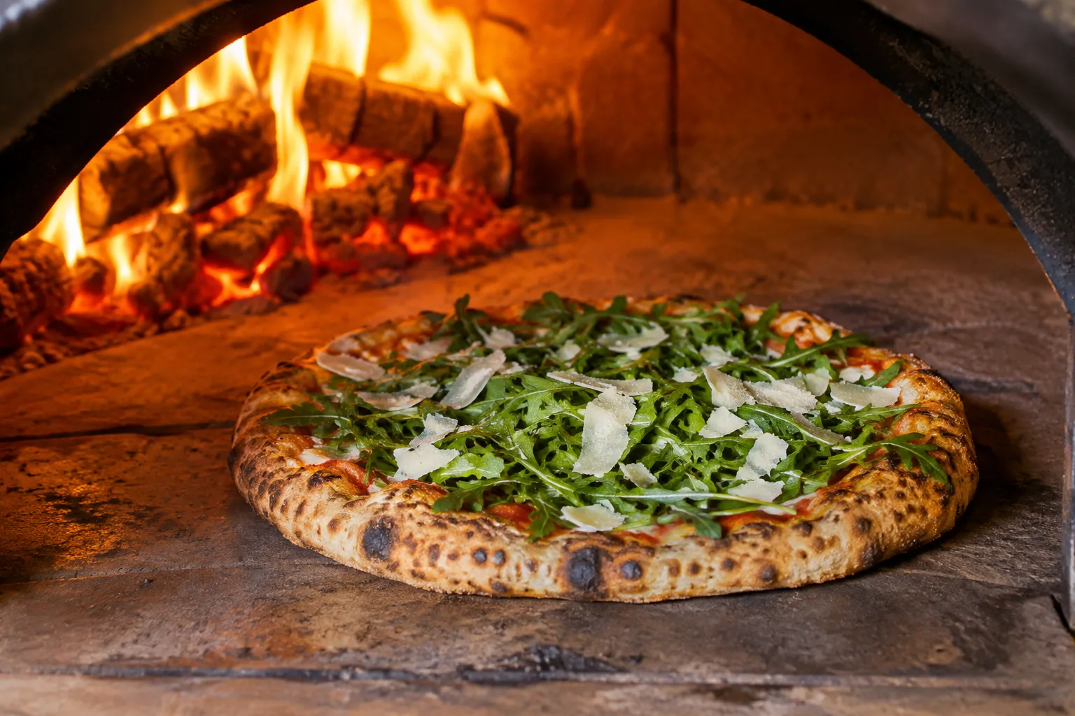 Pizza mit Rucola und Parmesan im Pizzaofen